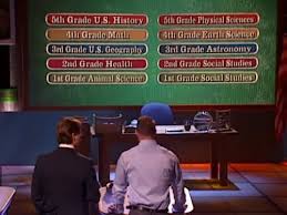 Two contestants on a game show stand at podiums, facing a green category board listing school subjects like U.S. History, Geography, and Astronomy.