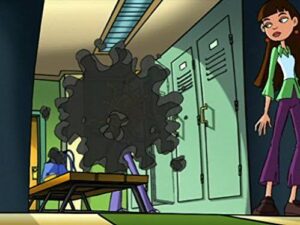 In a cartoon school hallway, a large black spiky virus model sits on a desk near green lockers, with a girl standing nearby.